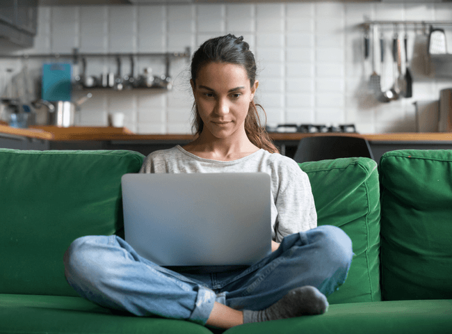 Serious woman using laptop checking email news online sitting on sofa